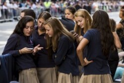 Sekelompok gadis sekolah Katolik melihat ponsel mereka saat mereka menunggu di rute yang akan diambil Paus Fransiskus di kemudian hari di dekat Katedral St. Patrick di New York, 24 September 2015. (Foto: Reuters)