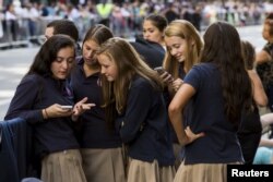 Sekelompok gadis sekolah Katolik melihat ponsel mereka saat mereka menunggu di rute yang akan diambil Paus Fransiskus di kemudian hari di dekat Katedral St. Patrick di New York, 24 September 2015. (Foto: Reuters)