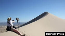 A sound engineer sets up to record singing sand dunes in the Mohave Desert, California. (Trevor Cox)