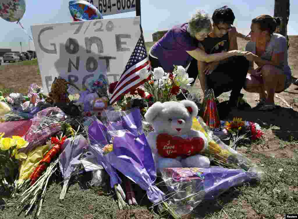 Isaac Pacheco (C) is comforted after leaving a birthday card for his friend Alex Sullivan, who was killed in the Denver-area movie killings, at a memorial site for victims behind the theater where a gunman opened fire on moviegoers in Aurora, Colorado Jul