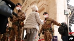 Police officers and soldiers check passengers leaving from Milan main train station, Italy, Monday, March 9, 2020. Areas under lockdown include Milan, Italy's financial hub and the main city in Lombardy, Venice, nd Veneto. (AP Photo/Antonio Calanni)