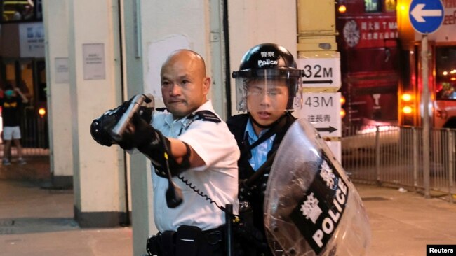 2019年7月30日一名警察举枪瞄准了在香港葵涌警署大楼前声援被拘捕的反送中抗议者的示威人群。
