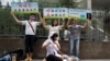 同性恋权利活动人士在北京一家法院外表演和抗议对同性恋实施的电击转化治疗。（2014年7月31日）