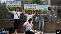 FILE - Gay rights campaigners act out electric shock treatment to protest outside a court where the first court case in China involving so-called conversion therapy is held in Beijing, China, July 31, 2014. A gay man in Henan province has now successfully sued a mental hospital over forced conversion therapy.