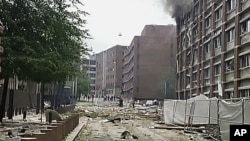 ပေါက်ကွဲမှုကြောင့် ထိခိုက်ပျက်စီးခဲ့သည့် အဆောက်အဦးတခုမှထွက်ပေါ်လာသည့် ပျက်စီးစများနှင့် မီးခိုးများကို တွေ့မြင်ရပုံ (ဇူလိုင်လ ၂၂၊ ၂၀၁၁)