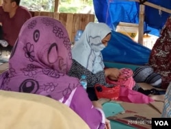 Pengungsi perempuan asal Afghanistan sedang menyulam di tenda pengungsi seberang Rudenim Jakarta hari Rabu (19/6). (Foto: VOA/Sasmito)