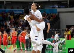 United States' Diana Taurasi, right, leaps into the arms of teammate Angel McCoughtry as they celebrate their win over Spain in a women's gold medal basketball game at the 2016 Summer Olympics in Rio de Janeiro, Brazil, Aug. 20, 2016.