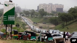 FILE - Cars queue up to buy fuel at a petrol station in Abuja, Nigeria, April 1, 2016. A series of bombings of pipelines and oil facilities have cut Nigeria's daily oil production of around two million barrels by as much as half.