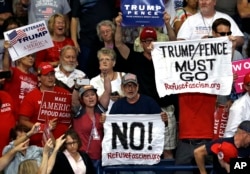 Protesters hold up signs during a rally as President Donald Trump speaks at the Covelli Centre in Youngstown, Ohio, July 25, 2017.