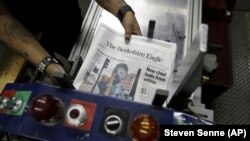 In this Thursday, April 11, 2019 photo, copies of The Berkshire Eagle newspaper are placed in a machine before being bundled for distribution, in Pittsfield, Mass. (AP Photo/Steven Senne)