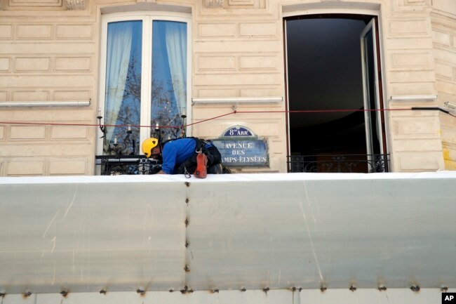 A worker sets up protections on the famed restaurant Fouquet's of the Champs Elysees, in Paris, March 22, 2019. French President Emmanuel Macron has announced that soldiers will be deployed across the country to help maintain security during yellow vest protests.