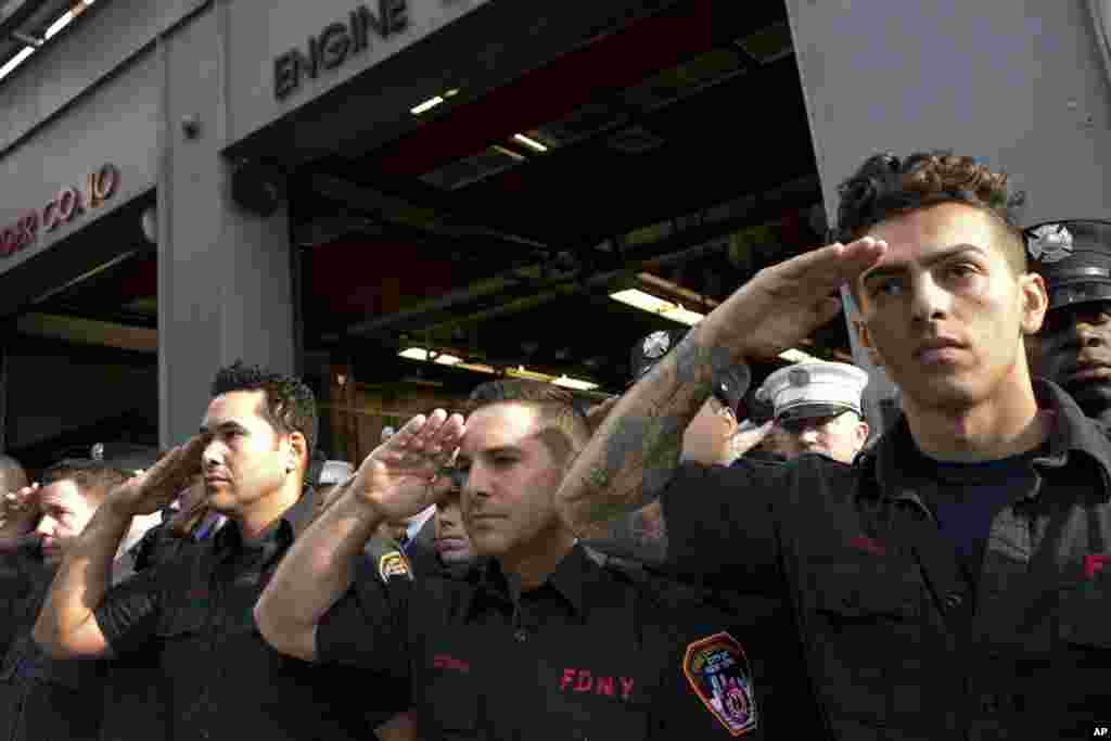 New York City firefighters with Ladder 10 Engine 10 firehouse salute during a moment of silence, Sept. 11, 2017, at the World Trade Center in New York.