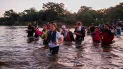 Los migrantes centroamericanos cruzan el río Suchiate desde Guatemana hacia México el 23 de enero de 2020 con el agua hasta la cintura por un sector donde no había tropas mexicanas cuidando la frontera.