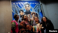 FILE PHOTO: A group of women pose for a photo in front of a poster advertising the film "Black Panther" on its opening night of screenings in Manhattan, New York, U.S., February 15, 2018. REUTERS/Andrew Kelly/File Photo