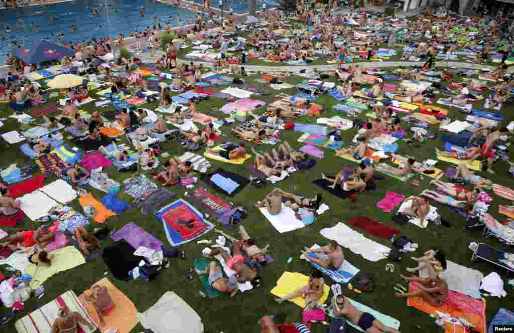 People relax at the public swimming pool of Schoenbrunner Bad on a sunny day in Vienna, Austria.