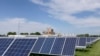 A solar panel array collects sunlight with the Fremont, Neb., power plant seen behind it, May 31, 2018. The Biden administration announced Monday that it would waive tariffs on solar panels imported to the United States from Cambodia, Malaysia, Thailand and Vietnam for 24 months.