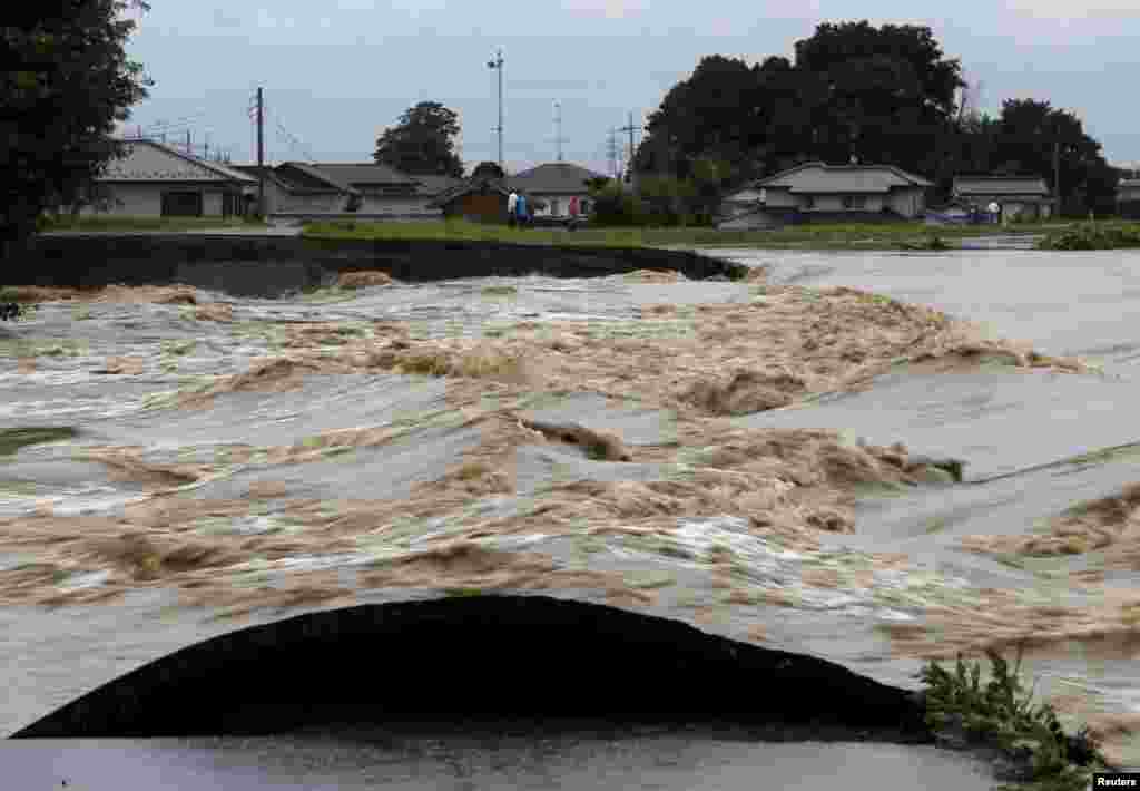 Floodwaters are seen at a break in the dike of the Kinugawa river (R) at a residential area flooded by the river, caused by typhoon Etau in Joso, Ibaraki prefecture, Japan, September 10, 2015. Unprecedented rain in Japan unleashed heavy floods on Friday t