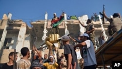 Rebels and their supporters celebrate around the iconic statue of a golden fist crushing a US military bomber outside Libyan leader Moammar Gadhafi's heavily damaged Bab al-Azizya compound in the center of Tripoli on August 24, 2011