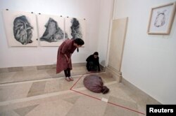 Visitors look at a latex russet-colored sack designed to feel like human skin, at an exhibition in Islamabad, April 3, 2013.