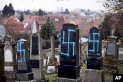 FILE - Vandalized tombs with tagged swastikas are pictured in the Jewish cemetery of Quatzenheim, eastern France, Feb.19, 2019.