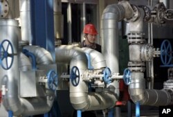 FILE - A Chinese worker walks past equipment at an oil refinery of the PetroChina Jilin Petrochemical Co. in Jilin, northeast China, May 24, 2004.