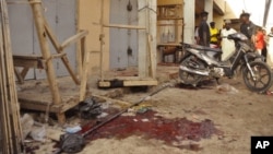 Nigerian troops gather evidence at the scene of suicide blasts that killed four people in Kano, Dec. 10, 2014. 