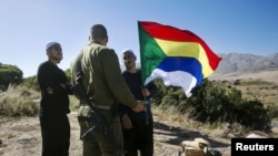 시리아 이슬람교 소수종파인 드루즈파의 한 남성이 드루즈 깃발을 들고 시리아와 이스라엘 국경 근처에서 한 이스라엘 군인에게 이야기 하고 있다(자료사진) 