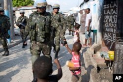 U.N. peacekeepers from Brazil bump fists with children as they patrol in the Cite Soleil slum, in Port-au-Prince, Haiti, Feb. 22, 2017. U.N. forces have patrolled since a 2004 rebellion engulfed the Caribbean country in violence.