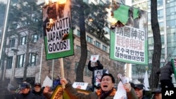 A South Korean protester holds burning placards during a rally against Japanese Prime Minister Shinzo Abe in front of the Japanese Embassy in Seoul, South Korea, Friday, Dec. 27, 2013.