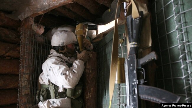 An Ukrainian Military Forces serviceman, watches through spyglass in a dugout on the frontline with Russia-backed separatists near Gorlivka, Donetsk region on Jan. 23, 2022.