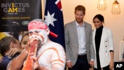 Britain's Prince Harry, center, and his wife Meghan, right, the Duchess Sussex attend a lunchtime reception hosted by Prime Minister Scott Morrison with Invictus Games competitors, their family and friends in the city's central parkland in Sydney, Austral