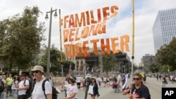 FILE - Demonstrators hold signs as they participate in the "Families Belong Together: Freedom for Immigrants" march in Los Angeles, June 30, 2018. 