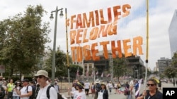 FILE - Demonstrators hold signs as they participate in the "Families Belong Together: Freedom for Immigrants" march, June 30, 2018, in Los Angeles. In major cities and tiny towns, marchers gathered across America, moved by accounts of children separated from their parents at the U.S.-Mexico border.