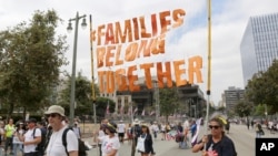 FILE - Demonstrators hold signs as they participate in the "Families Belong Together: Freedom for Immigrants" march, June 30, 2018, in Los Angeles. 