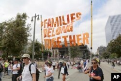 FILE - Demonstrators hold signs as they participate in the "Families Belong Together: Freedom for Immigrants" march, June 30, 2018, in Los Angeles.