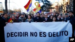 The president of Catalonian Parliament, Roger Torrent, center, and the Catalan regional President Quim Torra, center right, hold a placard that reads in Spanish: " To Choose is not a Crime", outside the Spanish Supreme Court in Madrid, Feb. 12, 2019.