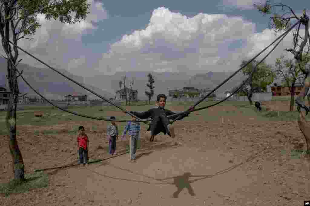 A boy plays on a makeshift swing on a hot summer day on the outskirts of Srinagar, Indian controlled Kashmir.