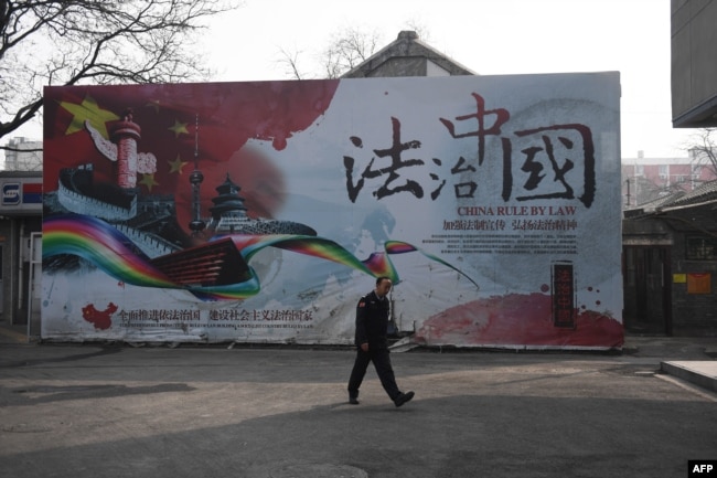 一名保安走过法治中国的广告牌。（2018年3月13日）
