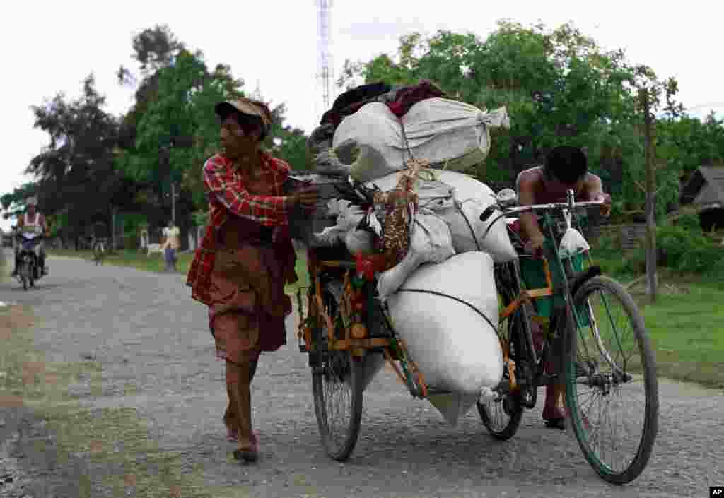 Local residents push a trishaw vehicle carrying their belongings in a village in Sittwe, where sectarian violence is impacting on the local population, June 11, 2012.