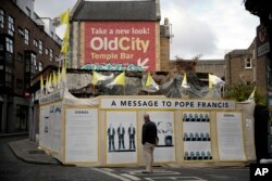 A passer-by looks at an art installation protesting the pope's visit, in Dublin, Ireland, Aug. 24, 2018.