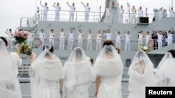 中國解放軍海軍人員在舟山一處軍事基地舉行的集體婚禮上揮手向他們的新娘告別（2017年12月29日）