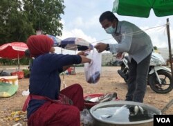 អ្នកស្រី រ៉ ហ្សា​ កំពុង​អង្គុយលក់​ត្រី​នៅ​ក្បែរ​ផ្លូវ​ជិត​មាត់​ទន្លេ​ក្នុង​សង្កាត់ជ្រោយ​ចង្វារ រាធានី​ភ្នំពេញ នៅ​ថ្ងៃ​ទី​២២ ខែ​ឧសភា ឆ្នាំ​២០២១។​ (កាន់ វិច្ឆិកា/វីអូអេ)