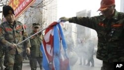 Former South Korean marines burn a North Korean flag during a rally, Saturday, Nov. 27, 2010, in Seoul, South Korea. South Korea is gearing up for joint military maneuvers with the U.S. starting Sunday that are likely to keep tensions soaring following th