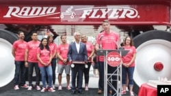 With the company's giant wagon as a backdrop and Chicago Mayor Rahm Emanuel looking on, Radio Flyer's Robert Pasin speaks at the company's 100th anniversary event in Chicago, July 13, 2017.