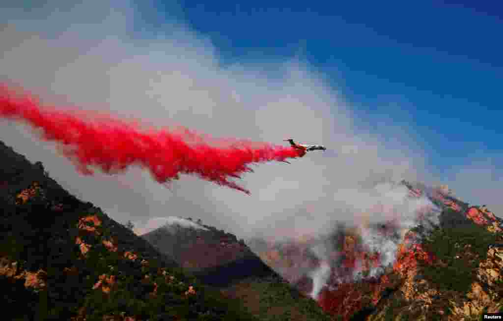 An aircraft drops flame retardant as firefighters battle the Woolsey Fire as it continues to burn in Malibu, California, Nov. 11, 2018.