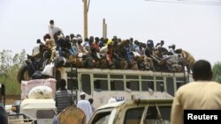 FILE: In an earlier time before the conflict now tearing Sudan apart, people ride on a bus as they return to their families ahead of the Eid al-Adha festival in Khartoum, on Sept. 11, 2016. 