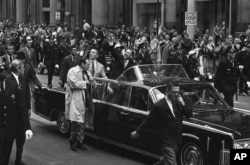 Apollo 13 astronauts John Swigert Jr., with his arms upraise and James Lovell ride in parade in their honor, Friday, May 2, 1970 through Chicago’s financial district as confetti streams from the skyscrapters.