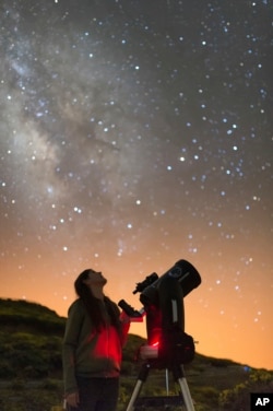 In this image released on Wednesday, July 11, 2018, an Experience guest observes the night sky with a telescope next to the Gran Telescopio Canarias at the Roque de los Muchachos Observatory on the island of La Palma in the Canaries, Spain. (Antoni Clader
