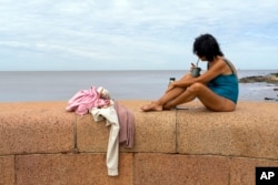 A woman has an herbal drink at the seaside in downtown Montevideo, Uruguay, Jan. 13, 2024.