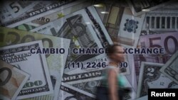 FILE - A woman walks past a currency exchange office in Sao Paulo, Brazil, Jan. 7, 2016.